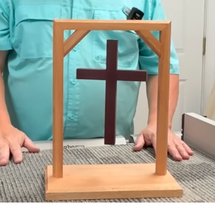 A handmade floating cross display in a wooden frame